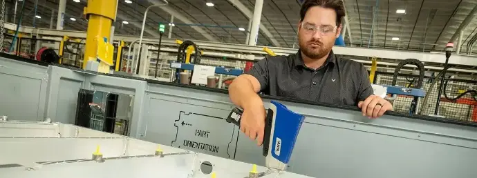 Técnico de calidad realizando una inspección PMI con un analizador XRF Vanta Core para verificar el grado de acero y prevenir errores de material en planta manufacturera.