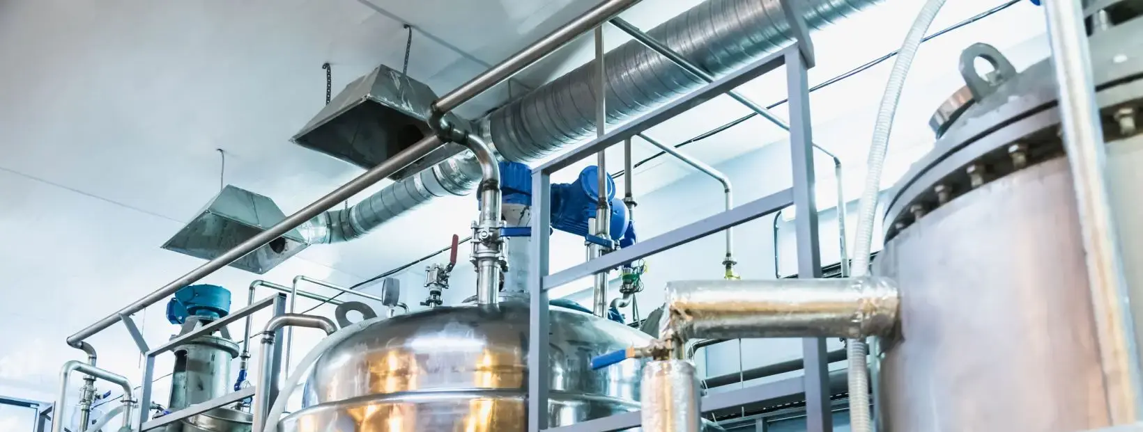 Tanques industriales y sistema de tuberías fabricados en acero inoxidable austenítico Serie 300 (Grados 304 y 316) en planta de procesamiento, ideales para inspección PMI contra la corrosión.