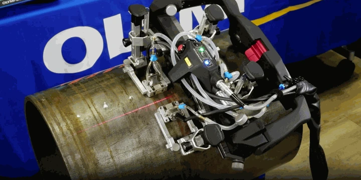 Primer plano del escáner semiautomatizado AxSEAM operando directamente sobre una tubería de acero. Se observa el módulo central guiado por una línea láser roja para mantener la precisión durante el escaneo de soldaduras de tuberías circunferenciales.