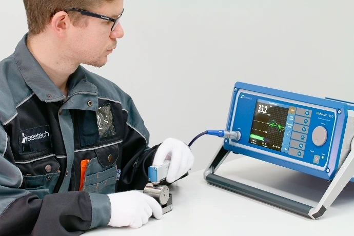 Técnico NDT midiendo esfuerzos residuales en pieza cilíndrica con sensor manual y Rollscan 350.